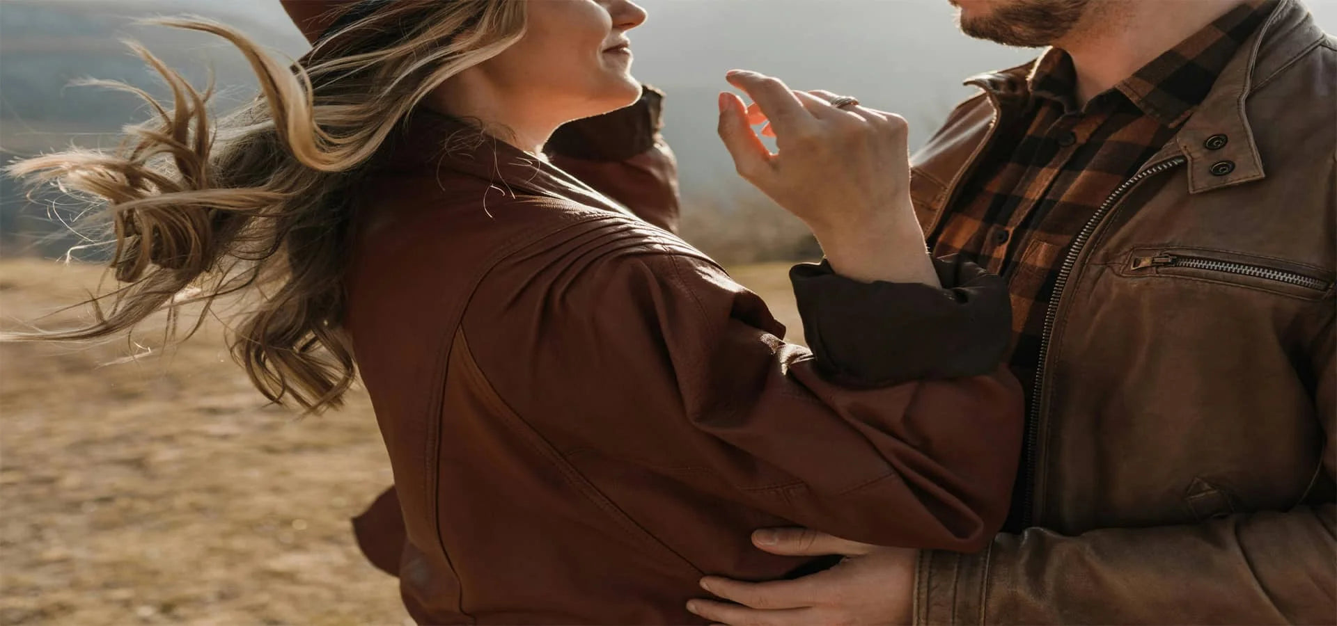 Couple wearing stylish brown leather jackets outdoors — men’s and women’s genuine leather outerwear.