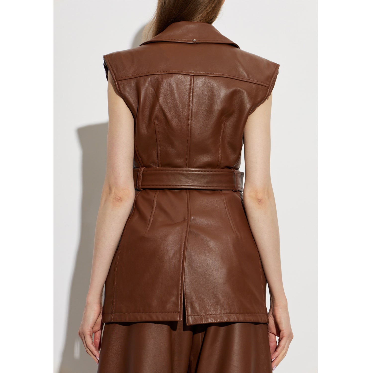 Back detail of women’s brown leather dress showing belt, vertical panel seams, and structured back yoke