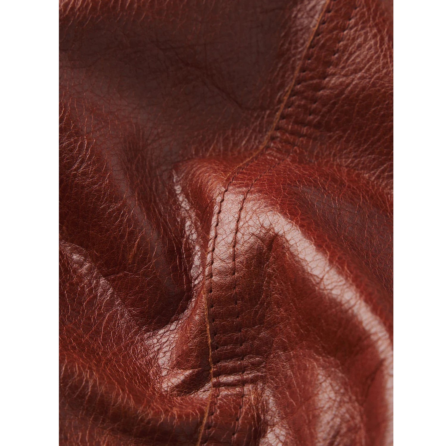 Close-up of textured brown leather with visible grain, stitching, and folds.